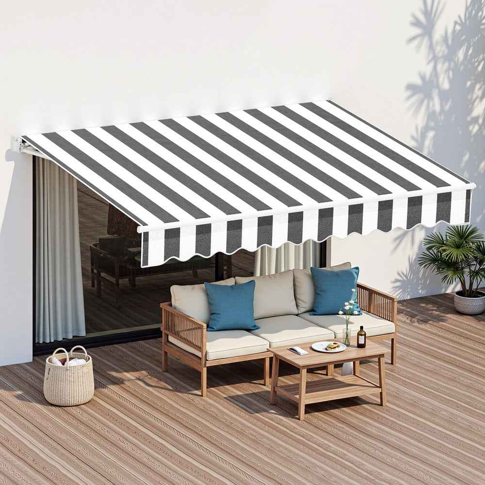 Retractable folding arm awning with black-and-white striped canopy over outdoor seating