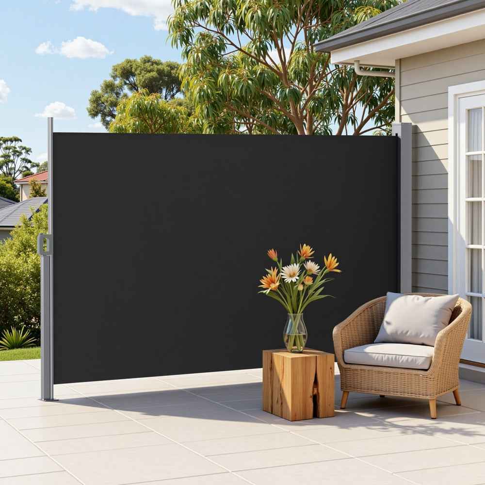 Black retractable side awning privacy screen with smooth fabric panel and armchairs