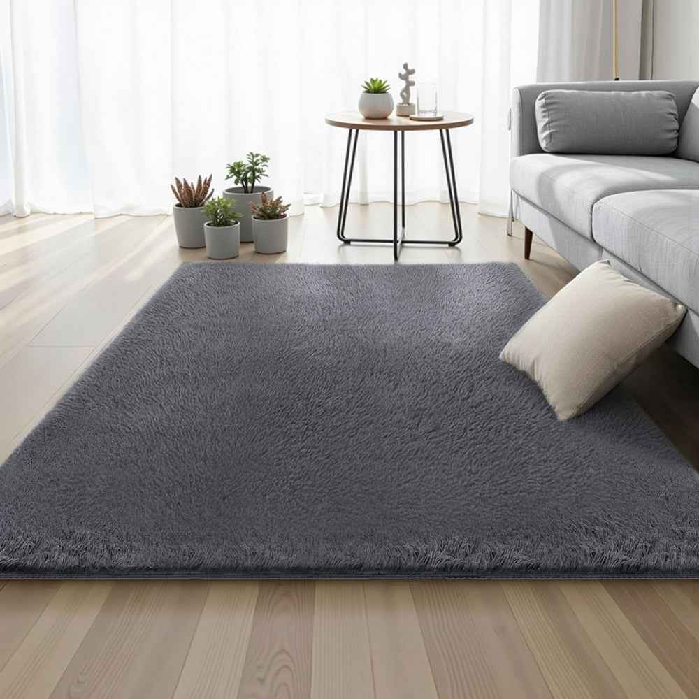 Grey plush shag area rug, smooth flat-top surface, rectangular size on floor.