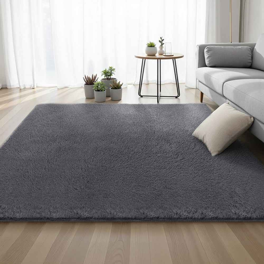 Grey plush shaggy area rug on wooden floor, rectangular shape