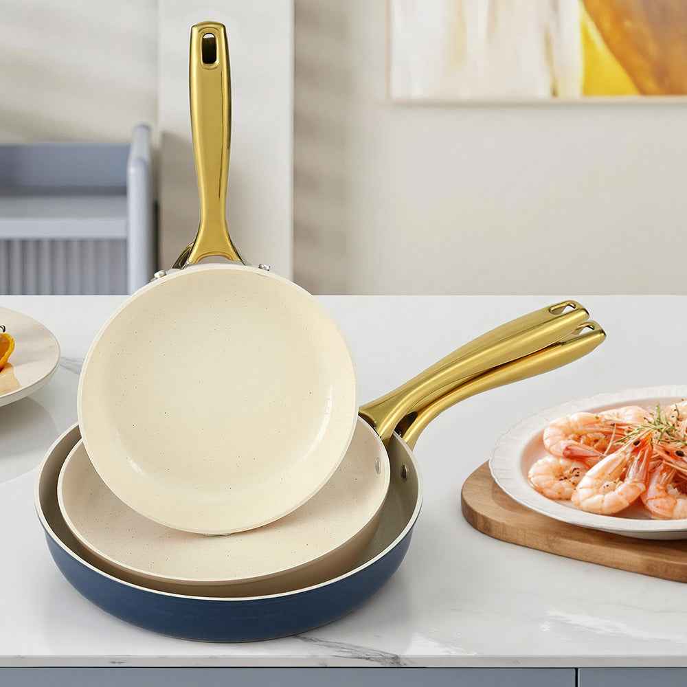 3-piece frying pan set with cream interiors, gold handles, navy rims