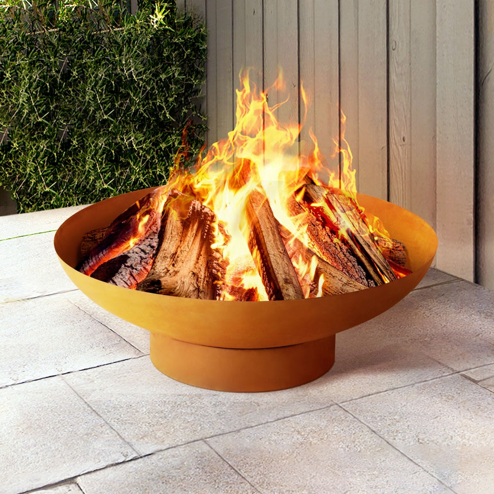 Rust-colored fire pit bowl with tall flames and stacked firewood