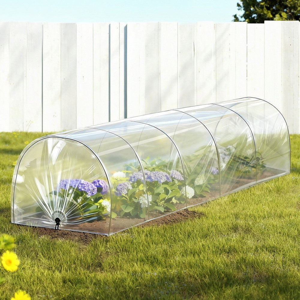 Clear tunnel greenhouse with arched steel frame over a garden plot