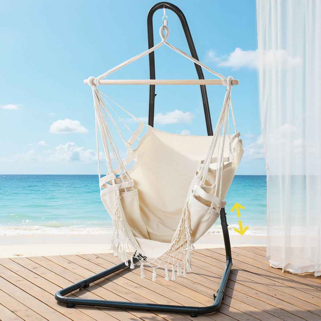 Cream hammock chair with netted sides, tassel fringe, and black steel stand