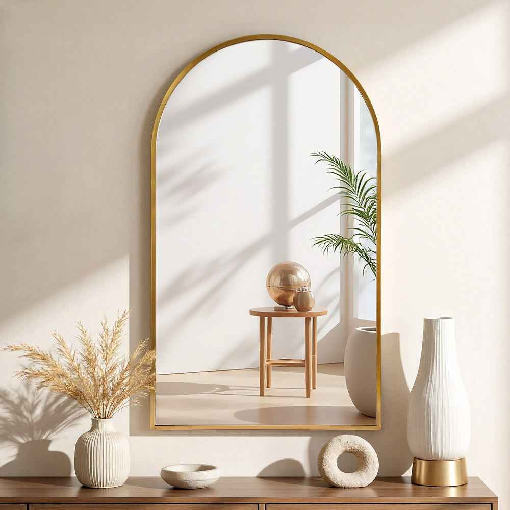 Arched wall mirror with gold-tone frame and reflective glass surface