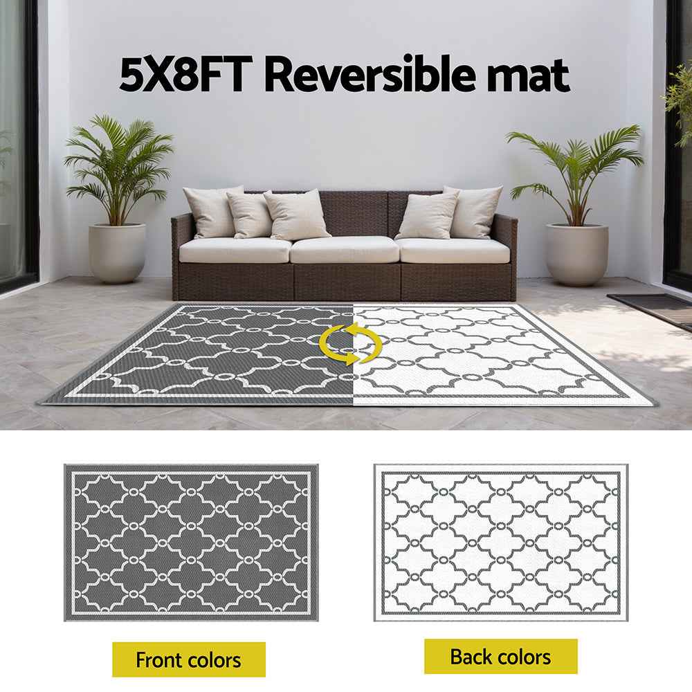 Reversible outdoor rug showing dark gray and white Moroccan lattice sides with centered split