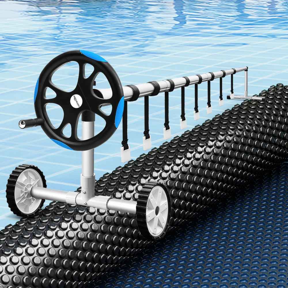 Black solar pool blanket with bubble texture and roller winder on pool edge
