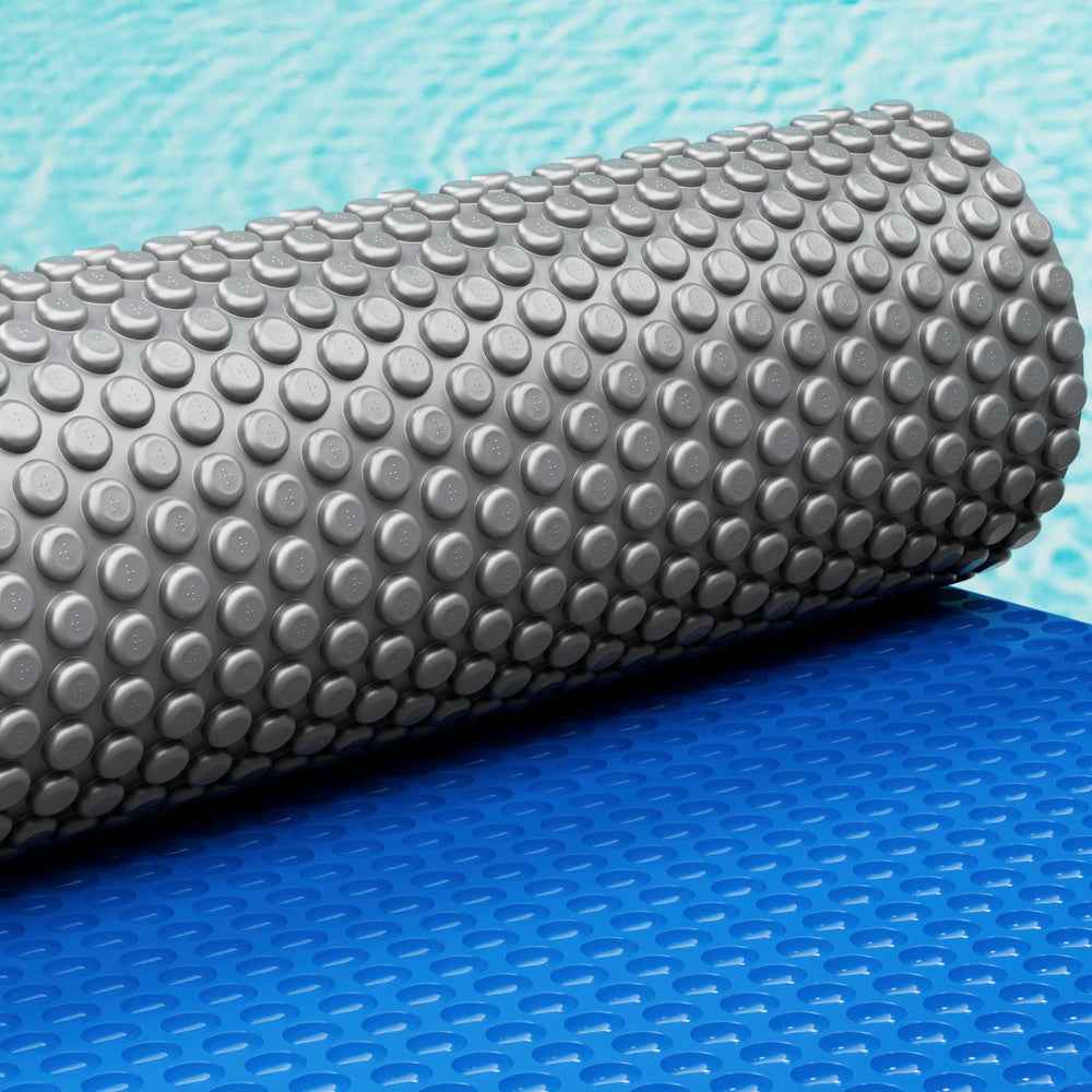 Rolled silver bubble pool solar blanket with raised domes over blue base