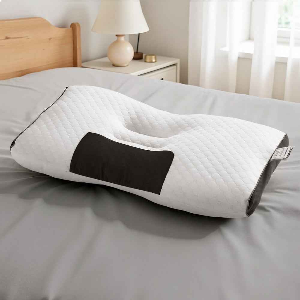 White ergonomic contour neck pillow with quilted cover and black support insert on bed