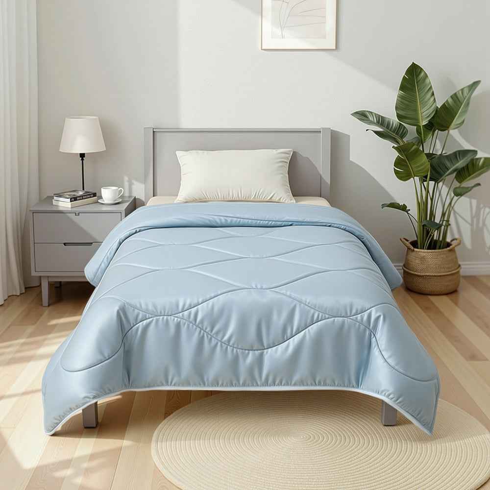 Light blue quilted comforter with stitched channel detailing on bed