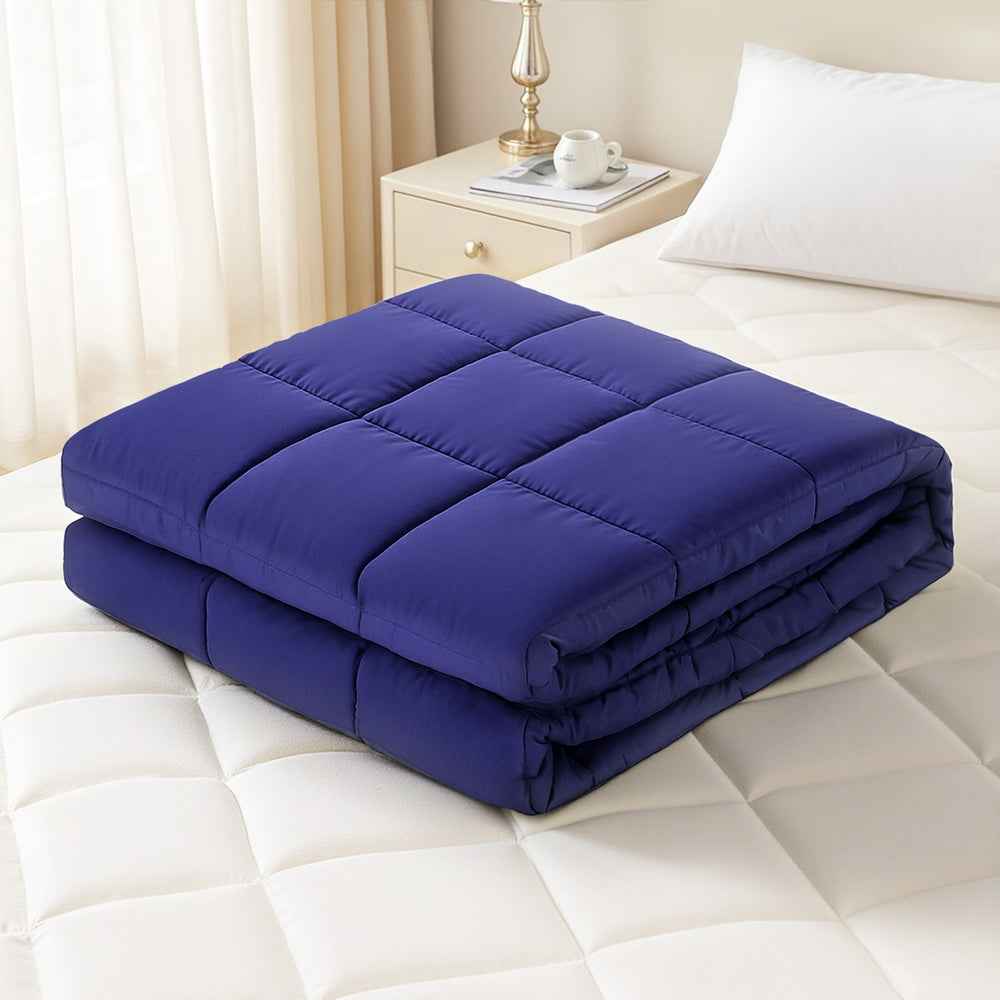 Blue weighted blanket, folded and displayed on a white bed