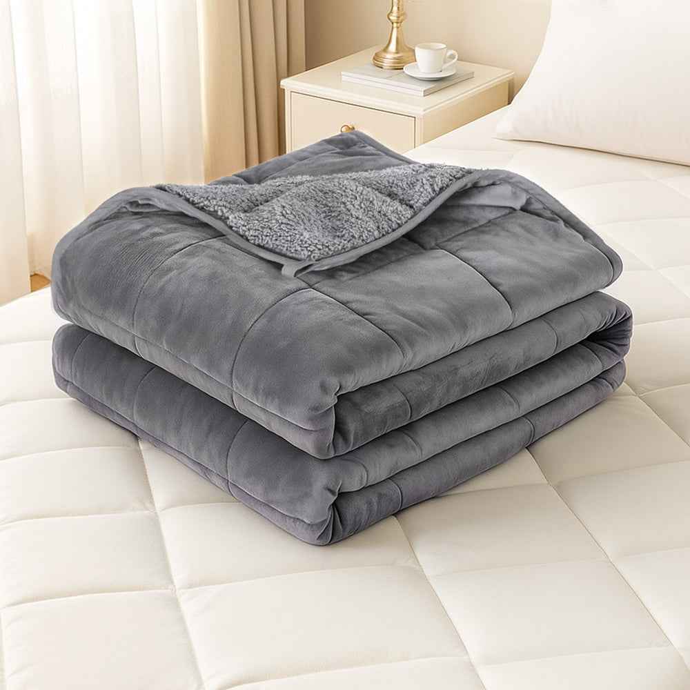 Grey weighted blanket folded on a bed, sherpa fleece edge visible.