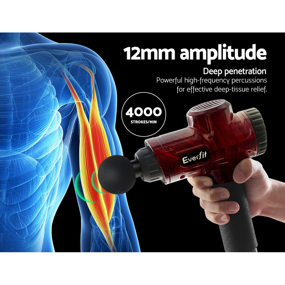 Red handheld massage gun held in hand with round head attachment