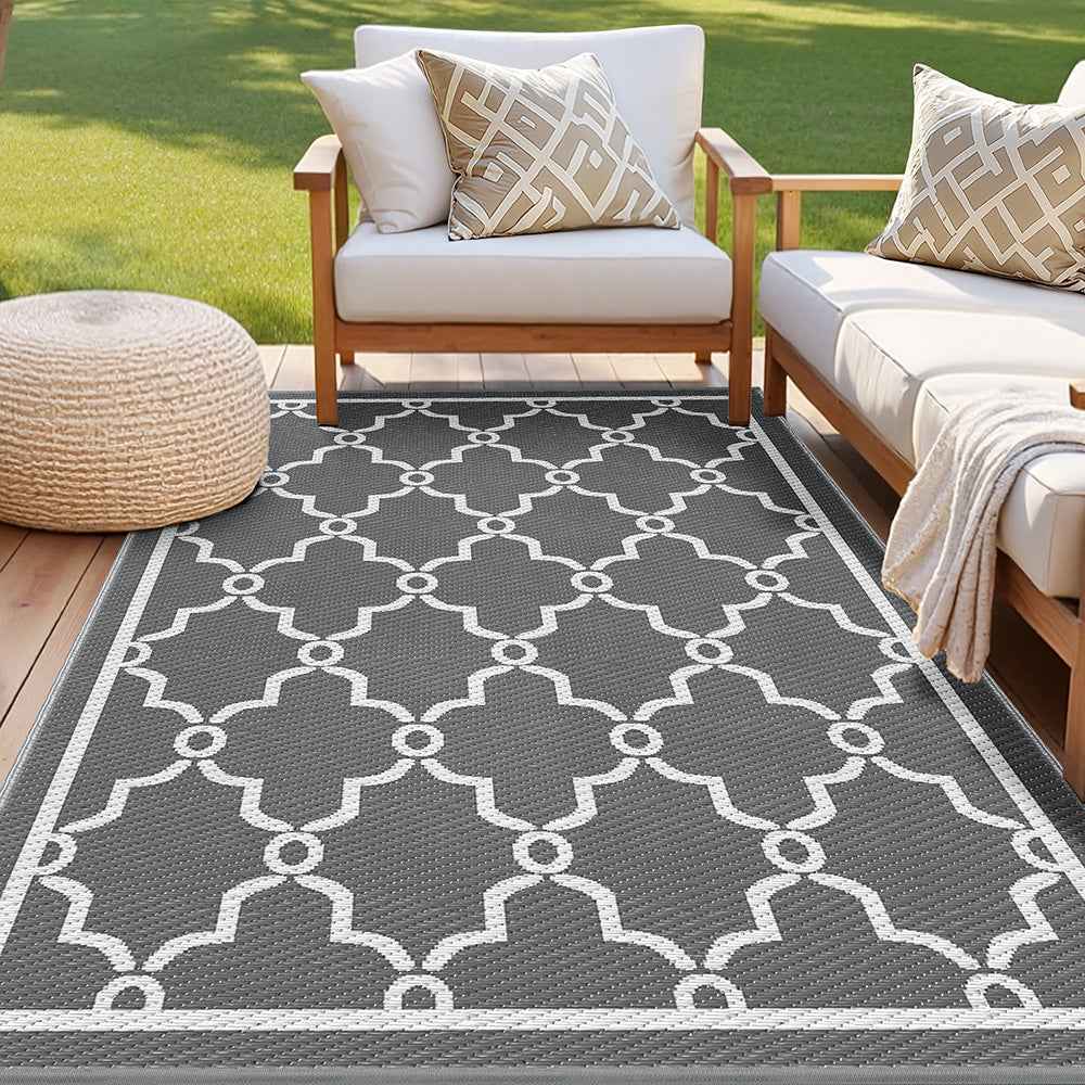 Large outdoor area rug with dark gray base and white Moroccan lattice quatrefoil pattern